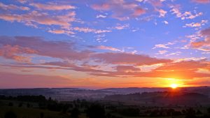 A sunrise with the sun rising bottom right into a blue dawn